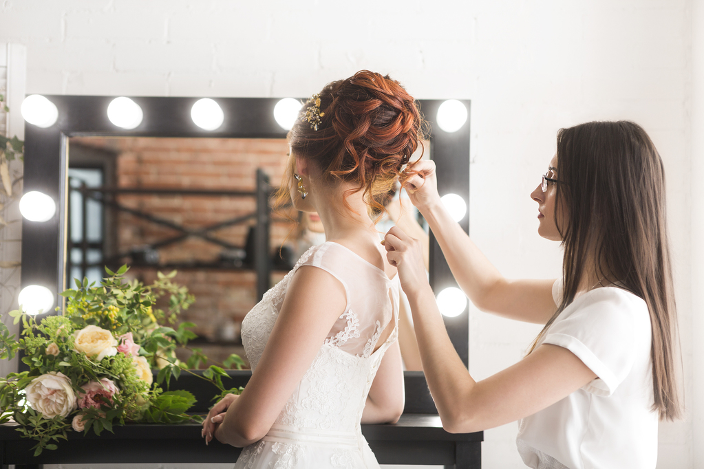Young pretty bride and stylist in studio before wedding ceremony